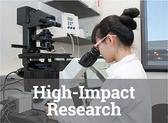 A woman in a lab coat looks through a microscope.