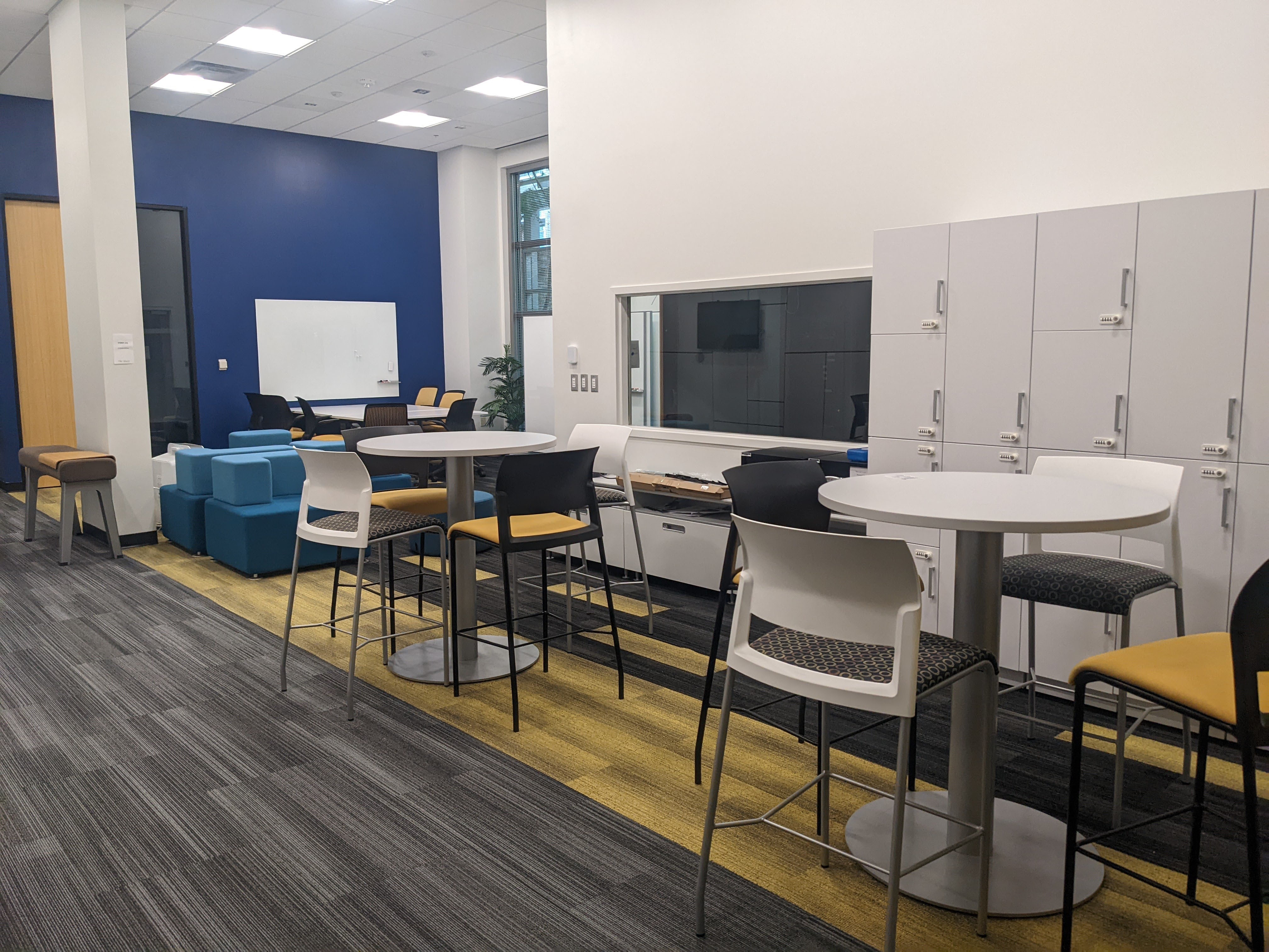 View of two high boy tables and chairs as well as lockers. 