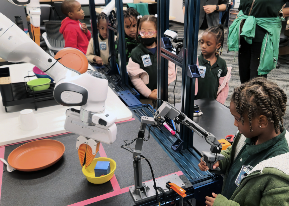 Elementary School student using a joystick interface to train a robotics arm.