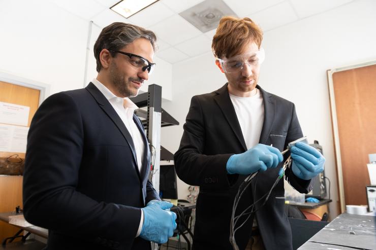 <p>Gleb Yushin, a professor in Georgia Tech’s School of Materials Science and Engineering and Kostiantyn Turcheniuk, research scientist in Yushin’s lab, inspect a battery using a new cathode design that replaces expensive metals and traditional liquid electrolyte with lower cost transition metal fluorides and a solid polymer electrolyte. (Credit: Allison Carter)</p>