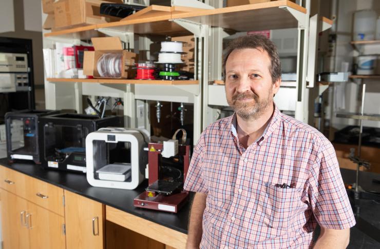 <p>Rodney Weber, a professor in Georgia Tech’s School of Earth &amp; Atmospheric Sciences,  stands in his lab alongside several consumer-grade 3D printers. (Credit: Allison Carter)</p>