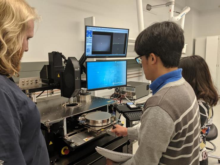 <p>Georgia Tech Associate Professor Shimeng Yu’s lab members (the two on right) perform semiconductor device testing on probe stations. Yu is helping solve the memory processing bottleneck issue. Merging the compute function with data storage in devices leads will improve energy and bandwith effiiencies by a factor of 10. (Photo credit: Shimeng Yu, Georgia Tech)</p>