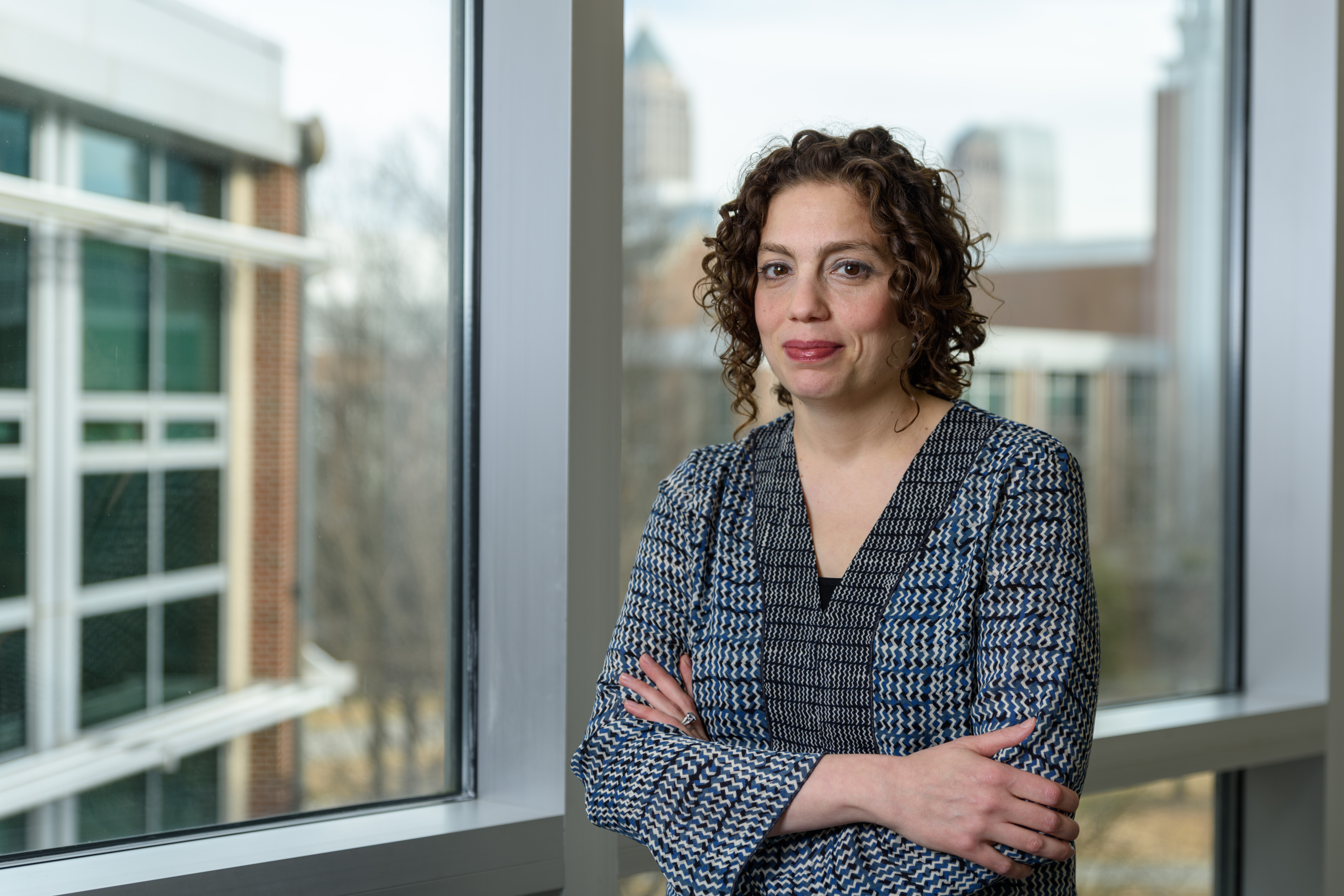 A woman stands in front of a window