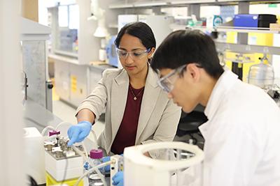 Akanksha Menon and colleague work at a lab bench.