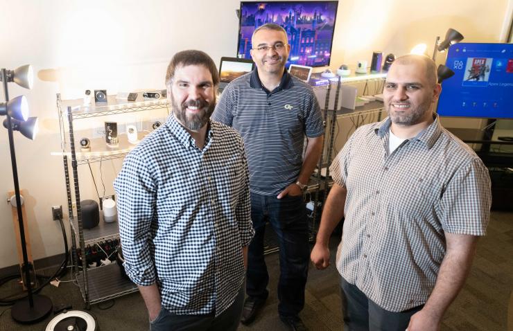 <p>Researchers Chaz Lever, Manos Antonakakis, and Omar Alrawi with a collection of internet-connected devices they have assessed in their lab. (Photo: Allison Carter, Georgia Tech)</p>