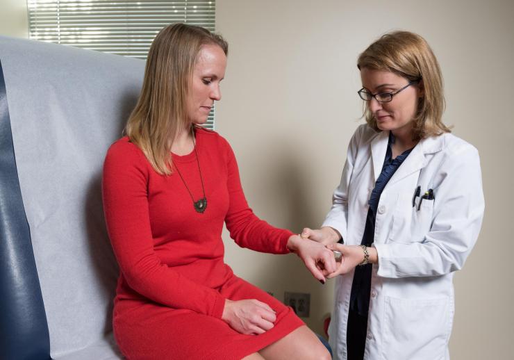 <p>Nadine Rouphael, M.D., associate professor of medicine (infectious diseases) at Emory University School of Medicine (standing) and study participant Daisy Bourassa, demonstrate how the microneedle vaccine patch was applied. (Credit: Rob Felt, Georgia Tech)</p>