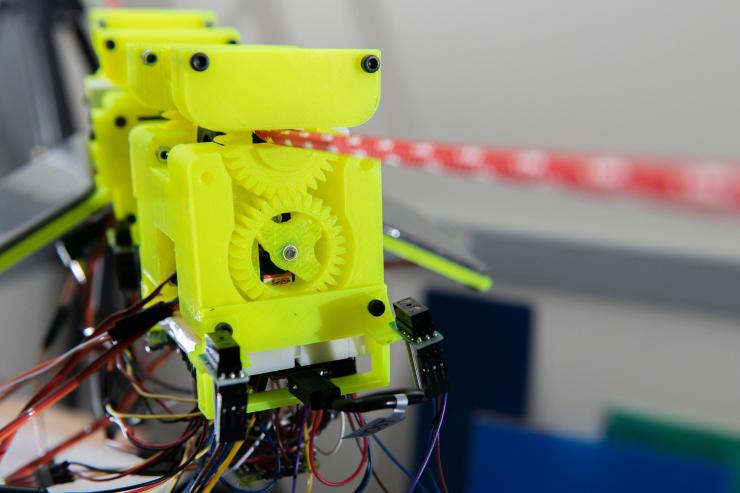 <p>Image shows components of the SlothBot, which is powered by two photovoltaic panels. 3D-printed gears and switches help the robot switch from one cable to another. (Photo: Allison Carter)</p>