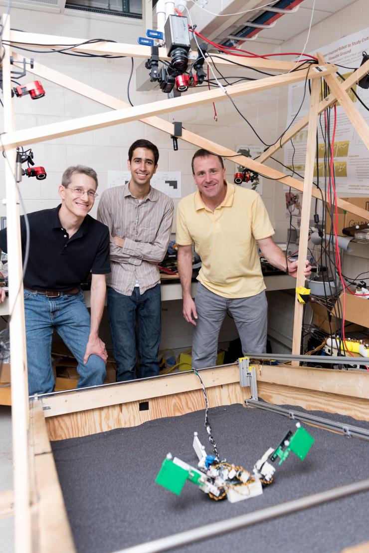 <p>Researchers (l-r) Richard Blob, Ben McInroe and Dan Goldman examine a robot named MuddyBot whose locomotion was inspired by the mudskipper. The robot has two limbs and a powerful tail to move though a trackway that can be raised to simulate granular slopes. Blob is a professor at Clemson University; McInroe was a student at Georgia Tech when the research was conducted, and Goldman is a professor at Georgia Tech (Credit: Rob Felt, Georgia Tech)</p>