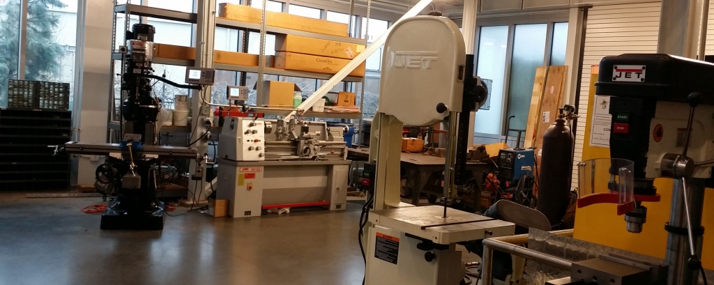 A view of the CNES machine shop including several tools such as a bandsaw, welders, bench grinder, etc.