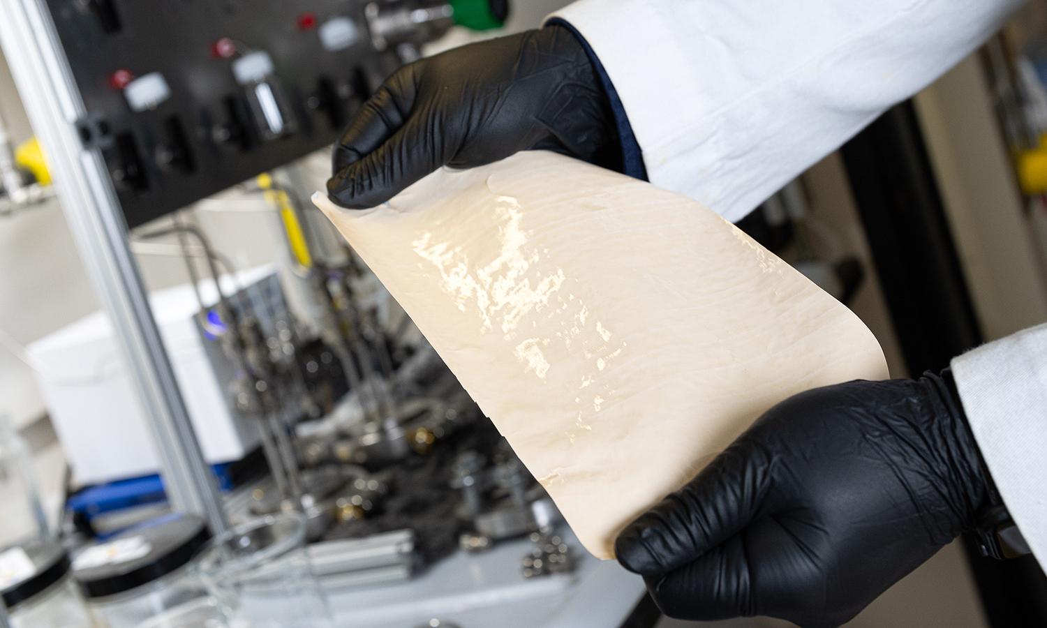 Two hands holding an example of the DUCKY polymer membranes researchers created to perform the initial separation of crude oils with significantly less energy. (Photo: Candler Hobbs)