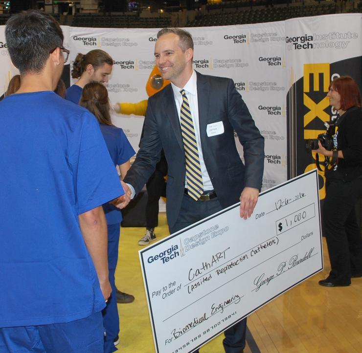 <p>James Rains congratulates a Capstone team during the Design Expo.</p>