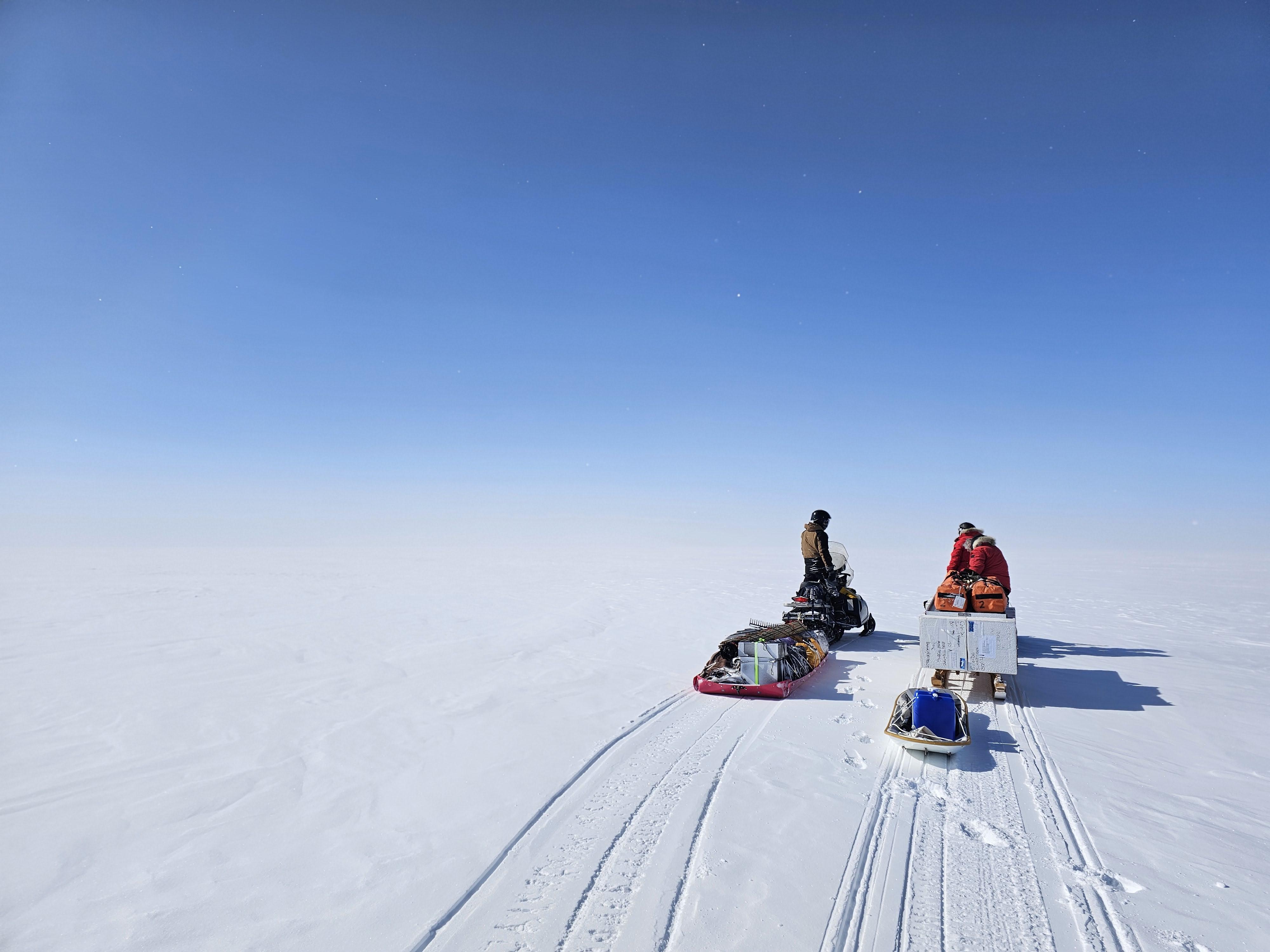 The team snowmobiling to a remote field site.