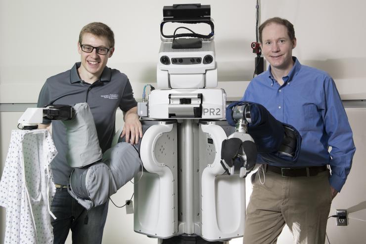 <p>A PR2 robot puts a hospital gown on human arms after teaching itself how to do it.</p>