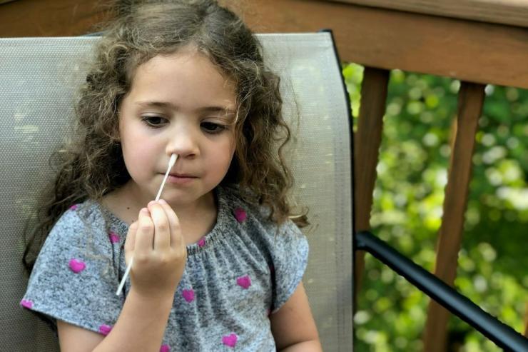 <p>A child swabs their nose for Covid-19 testing.</p>