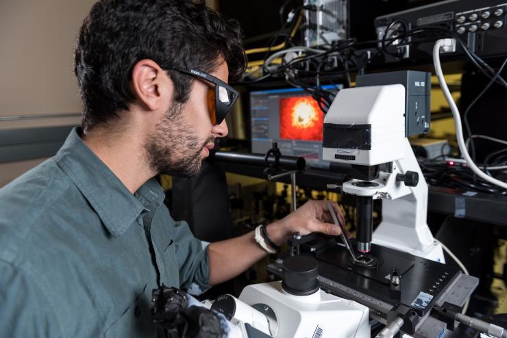 <p>Sean Rodrigues, a Ph.D. candidate in the Georgia Tech School of Electrical and Computer Engineering, adjusts a sample of a chiral metamaterial whose properties in the nonlinear regime produce a significant spectral shift with power levels in the milliwatt range. (Credit: Rob Felt, Georgia Tech)</p>