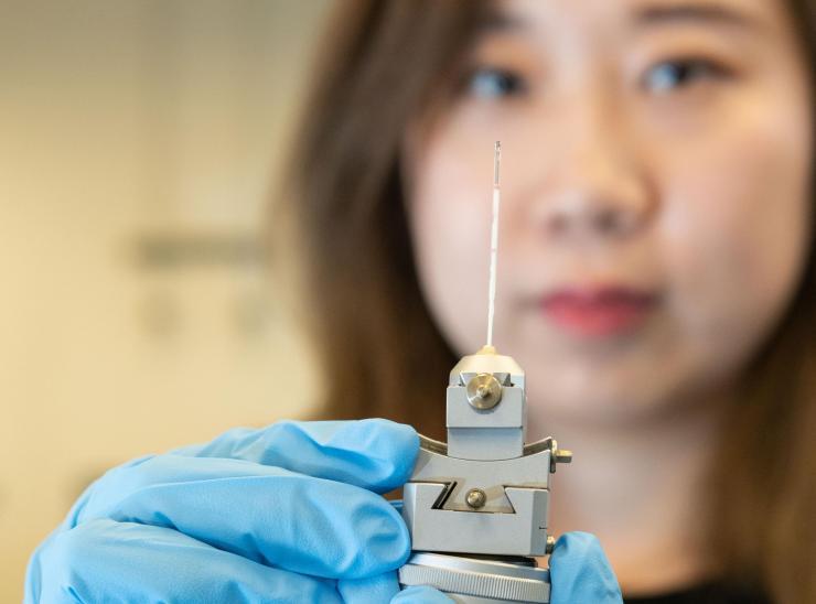 <p>Georgia Tech graduate research assistant Xuetian Ma holds a reaction vessel similar to those used in the research on nanoscale crystalline growth. The vessels were made of a high-strength quartz tube about a millimeter in diameter and about two inches long. (Credit: Allison Carter, Georgia Tech)</p>