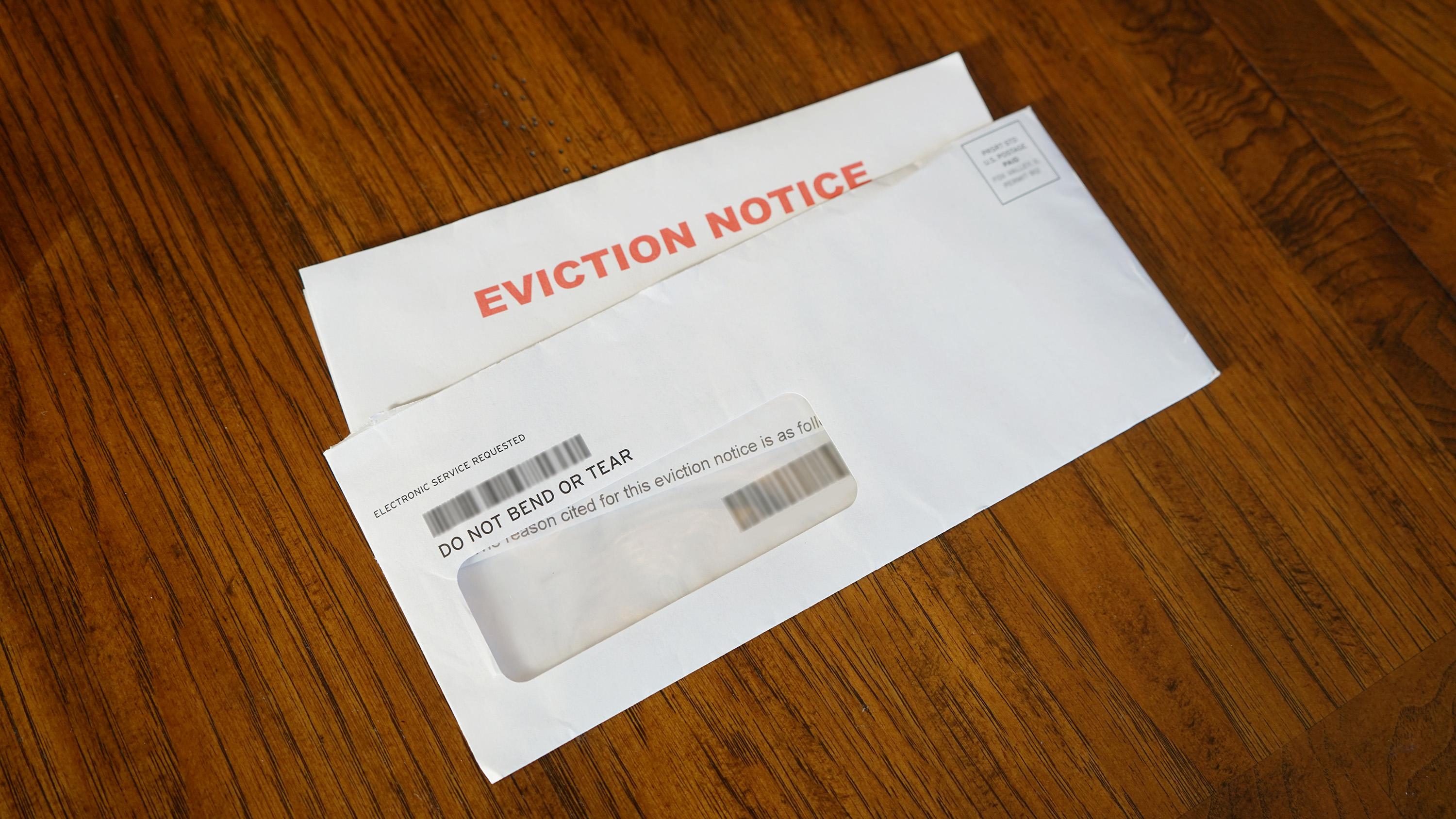 Image of a letter with the words "Eviction Notice" inside an envelope on a wood table.