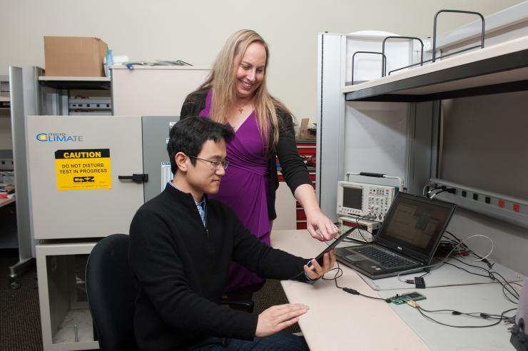 <p>Georgia Tech Graduate Research Assistant Sihwan Kim and Professor Jennifer Hasler are developing an application for the FPAA device. They are using design tools on the laptop computer and evaluating a demonstration on the handheld tablet driving the FPAA device. (Credit: Fitrah Hamid, Georgia Tech)</p>