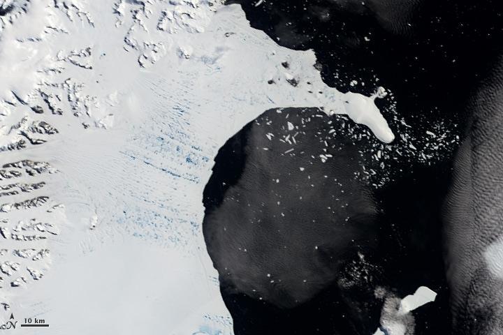 <p>Before its sudden shattering, numerous meltwater ponds riddled Antarctic ice shelf Larsen B. They are seen in this 2002 satellite image as a matrix of aquamarine spots. Scientists believe that the ponds hydrofractured the kilometer-thick ice shelf, causing its swift destruction. Credit: NASA Earth Observatory</p>