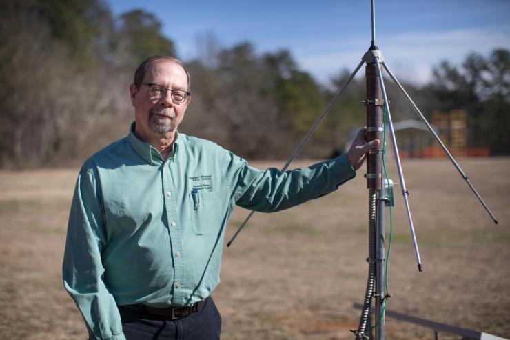 <p>John Trostel, director of the Severe Storms Research Center (SSRC), poses with a sensor that is part of the North Georgia Lightning Mapping Array, a network of 12 such sensors located around the metropolitan Atlanta area to detect lightning that may indicate storm intensification. (Credit: Branden Camp, Georgia Tech Research Institute)</p>