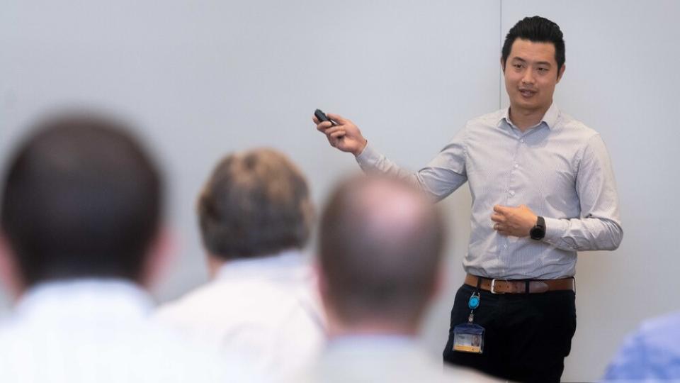 Man pointing at white board in front of a classroom