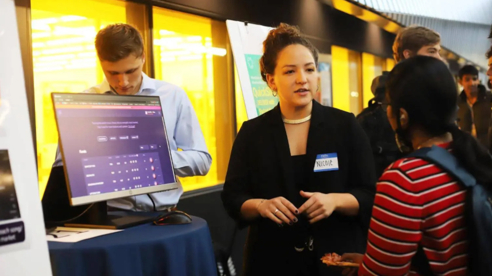 Two individuals talking in front of a computer screen